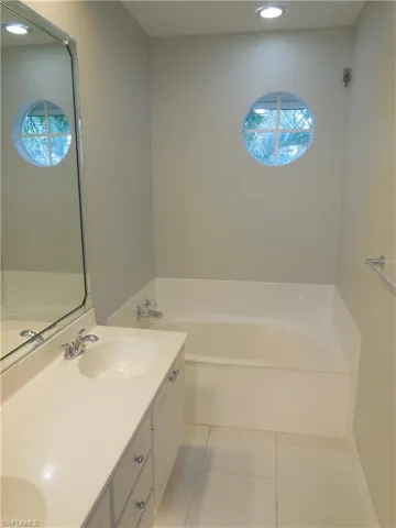 Bathroom featuring tile patterned floors, a tub to relax in, and vanity