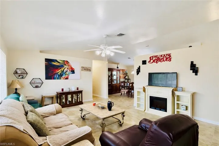 Living area with vaulted ceiling, ceiling fan, and a fireplace