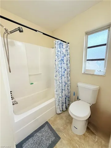 Bathroom featuring shower / tub combo with curtain and tile patterned floors