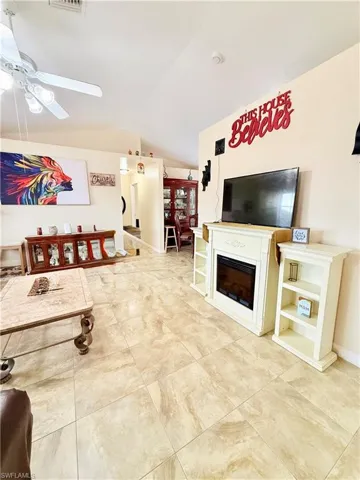 Living area with vaulted ceiling, a ceiling fan, and a fireplace