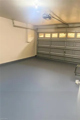 Garage featuring a garage door opener and baseboards