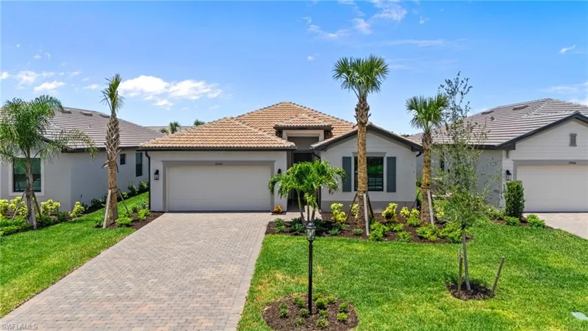Single story home with stucco siding, decorative driveway, an attached garage, a tiled roof, and a front lawn
