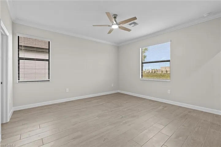 Unfurnished room with ceiling fan, light wood-style floors, crown molding, and baseboards