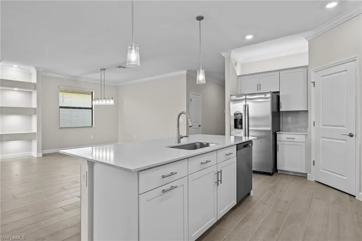 Kitchen with stainless steel appliances, a sink, light countertops, light wood-style flooring, and ornamental molding