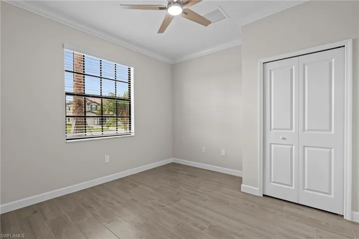 Unfurnished bedroom featuring ornamental molding, light wood-type flooring, baseboards, a closet, and a ceiling fan