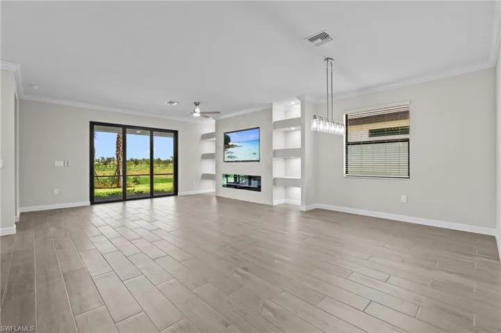 Unfurnished living room with ornamental molding, baseboards, ceiling fan, a fireplace, and light wood-type flooring