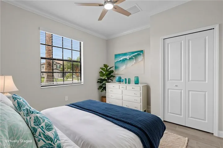 Bedroom with crown molding, light wood finished floors, a closet, and ceiling fan