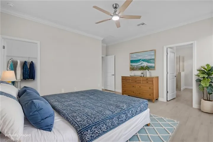 Bedroom featuring crown molding, light wood-style flooring, baseboards, a ceiling fan, and a closet