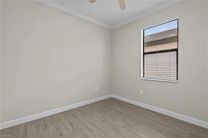 Unfurnished room featuring crown molding, baseboards, wood finished floors, and a ceiling fan