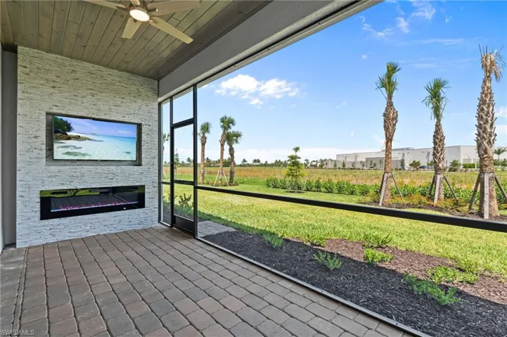 Unfurnished sunroom featuring a ceiling fan and an outdoor stone fireplace