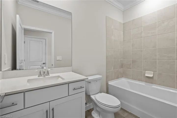 Full bath with crown molding, toilet, vanity, and bathing tub / shower combination
