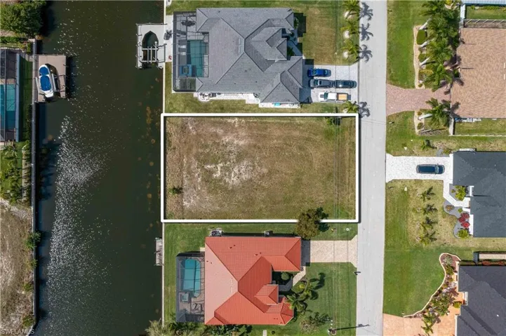 Aerial view of residential area with a large body of water and property parcel outlined
