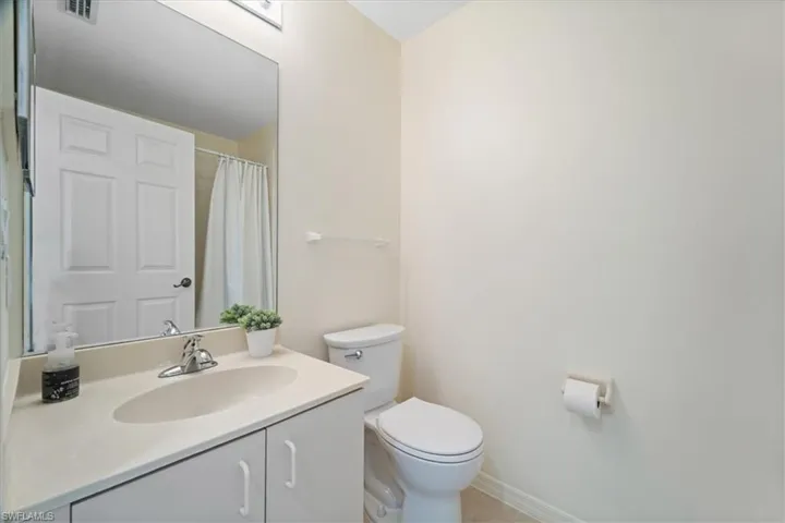Bathroom with toilet, vanity, baseboards, and visible vents