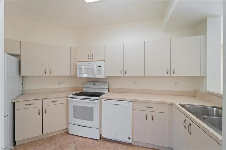 Kitchen featuring light countertops, a sink, and white appliances