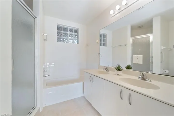 Full bath with a sink, tile patterned floors, a stall shower, and a garden tub