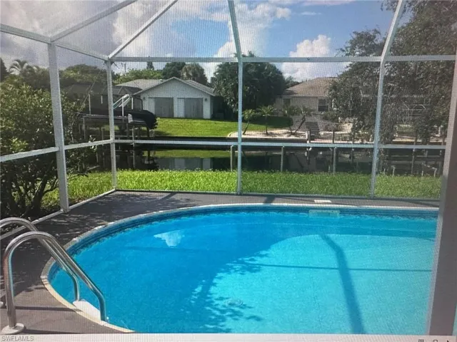 Outdoor pool with a sunroom, glass enclosure, and a yard