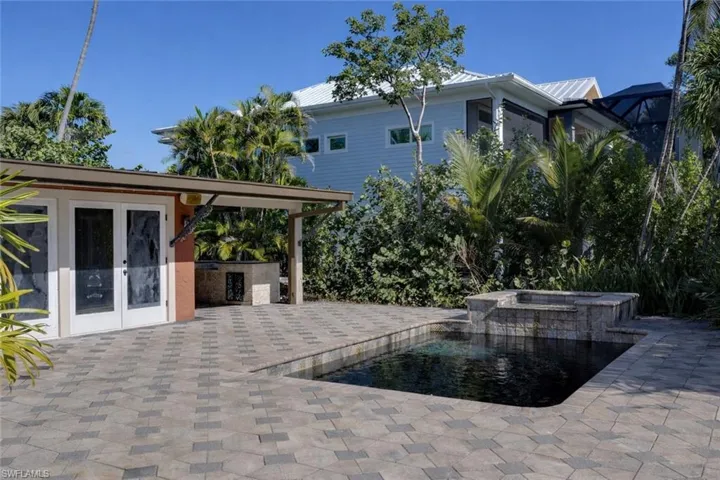 Relaxing pool / spa featuring french doors, a patio, and an outdoor kitchen