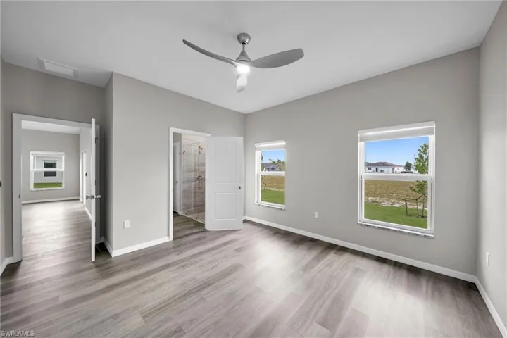 Unfurnished bedroom with ensuite bath, ceiling fan, and hardwood / wood-style flooring