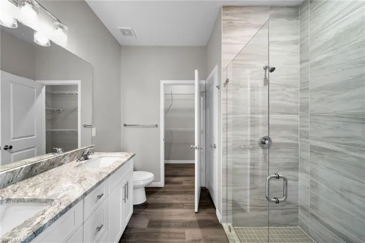 Bathroom featuring toilet, walk in shower, hardwood / wood-style flooring, and double sink vanity