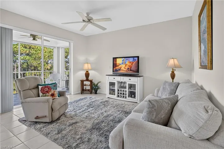 Living area featuring tile flooring, ceiling fan, and access to a screened balcony with an additional ceiling fan