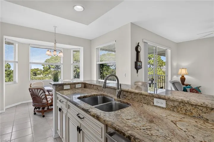 Kitchen featuring granite countertops, a double basin stainless steel sink, and white cabinetry with dark hardware