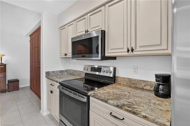 Kitchen featuring granite countertops, painted cabinetry, stainless steel oven, and an over-the-range microwave