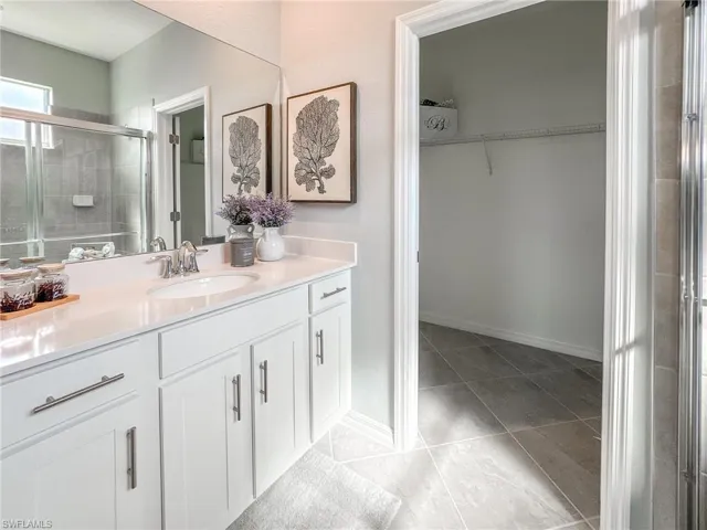 Bathroom featuring a stall shower, a walk in closet, vanity, and light tile patterned floors