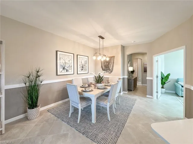 Dining room with arched walkways, light tile patterned floors, and a chandelier