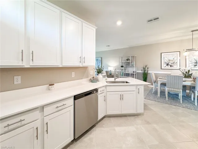 Kitchen with white cabinetry, dishwasher, a peninsula, hanging light fixtures, and light tile patterned floors