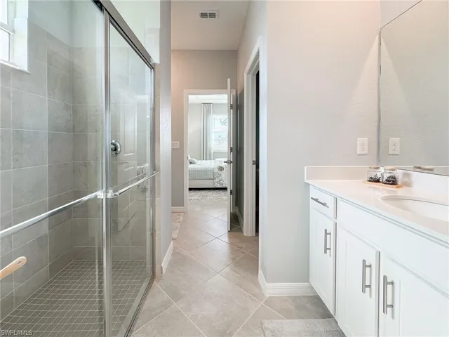 Ensuite bathroom with vanity, a shower stall, and light tile patterned floors