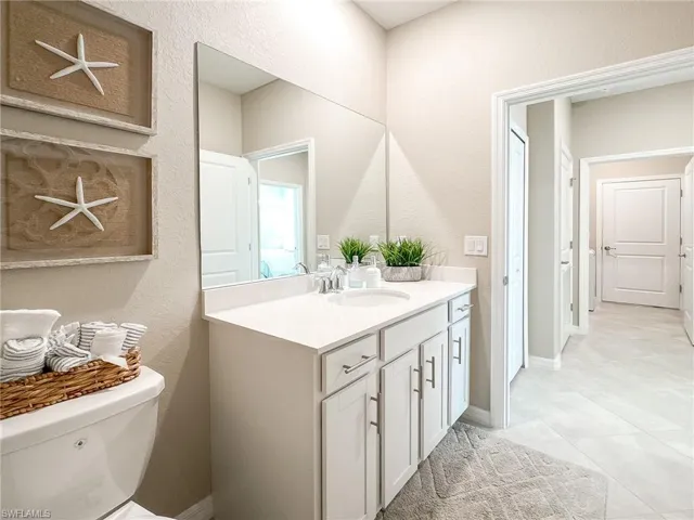 Half bathroom with vanity, a textured wall, and light tile patterned flooring
