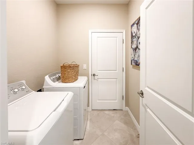 Laundry room with separate washer and dryer and baseboards
