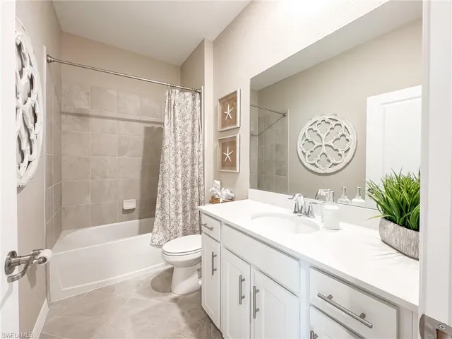 Full bath with shower / bathtub combination with curtain, light tile patterned floors, and vanity