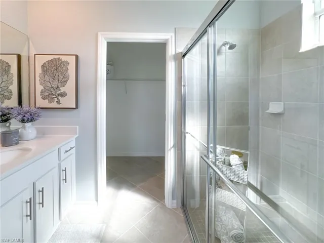 Bathroom with vanity, a stall shower, light tile patterned floors, and a spacious closet
