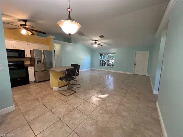 Kitchen featuring appliances, decorative light fixtures, light tile patterned floors, vaulted ceiling, and a ceiling fan