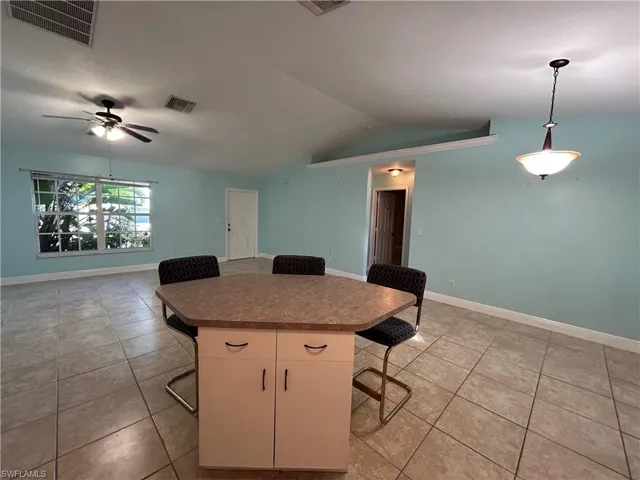 Kitchen with a kitchen breakfast bar, light tile patterned floors, pendant lighting, lofted ceiling, and open floor plan