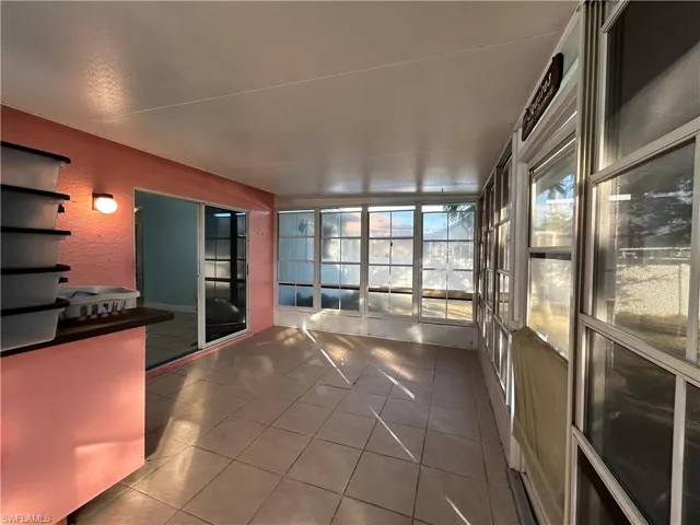 Unfurnished sunroom featuring tile patterned flooring and a textured wall