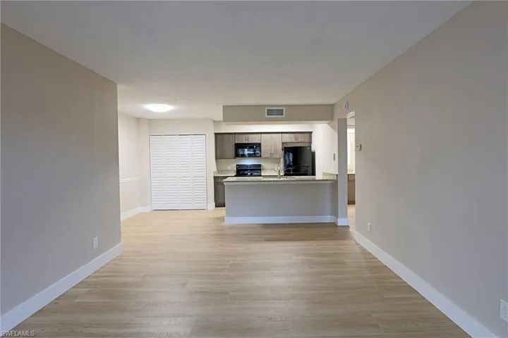 Unfurnished living room featuring light wood-style floors and baseboards