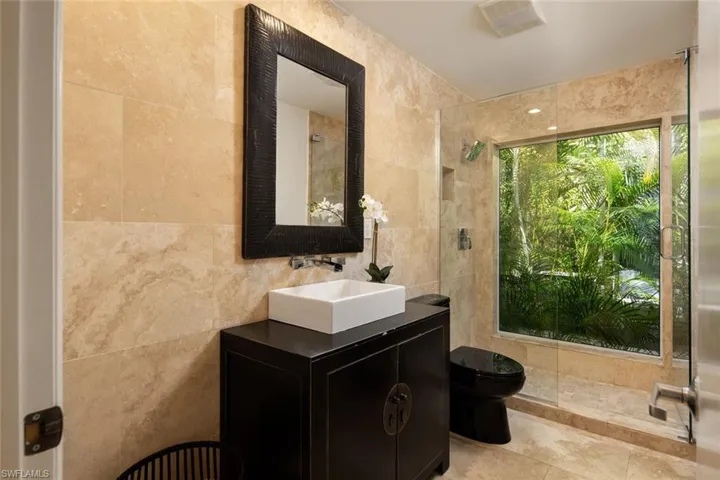 Bathroom featuring vanity, tile walls, and toilet