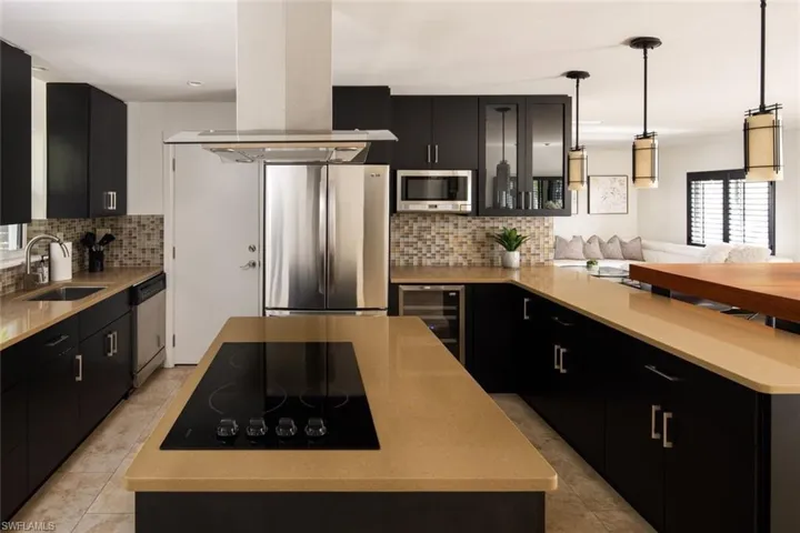 Kitchen with pendant lighting, island range hood, sink, beverage cooler, and stainless steel appliances