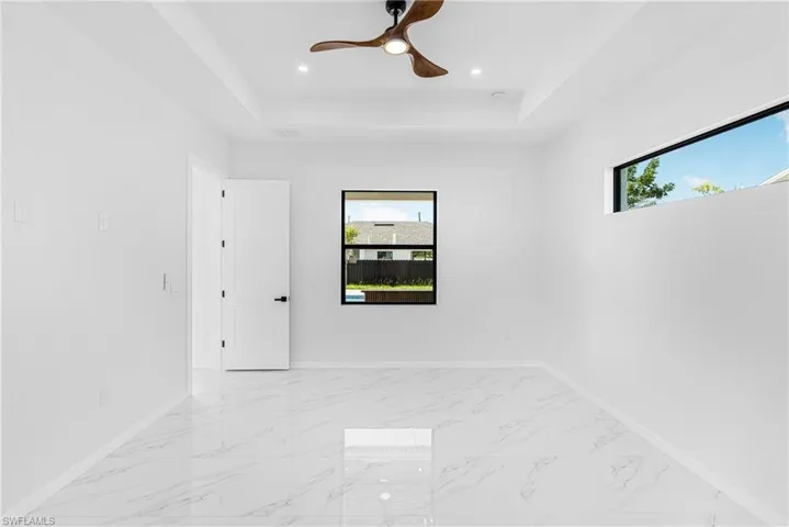 Empty room featuring marble finish floor, a tray ceiling, and a wealth of natural light