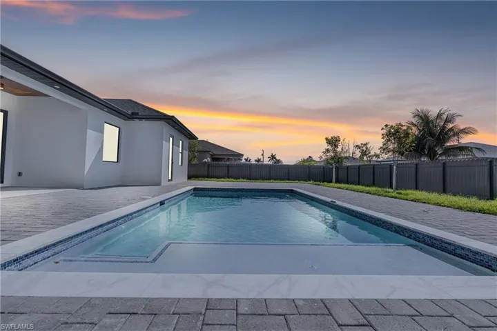 Pool at dusk featuring a patio area, a fenced backyard, and a fenced in pool