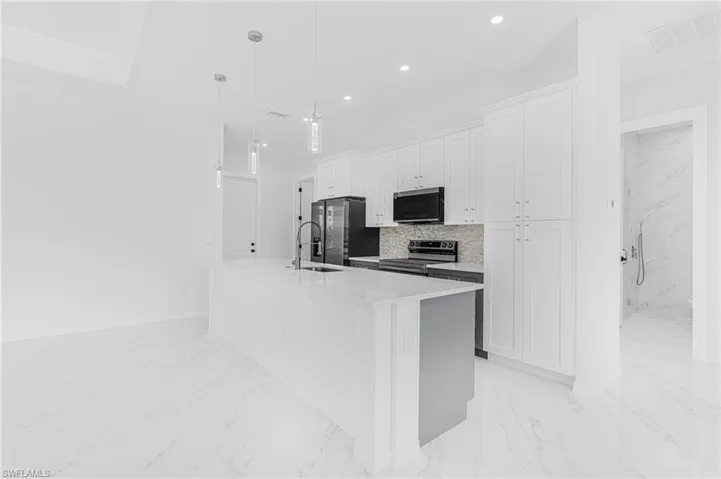 Kitchen with a center island with sink, visible vents, appliances with stainless steel finishes, marble finish floor, and a sink