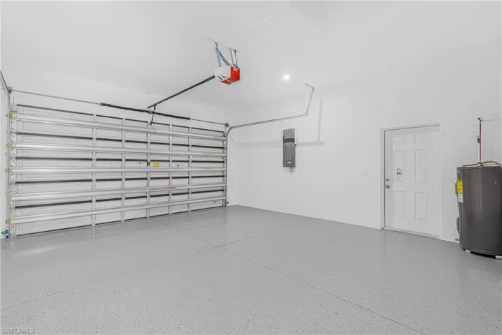 Garage with electric panel, a garage door opener, and electric water heater