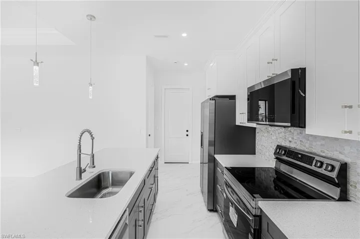 Kitchen featuring stainless steel appliances, a sink, white cabinetry, marble finish floor, and tasteful backsplash