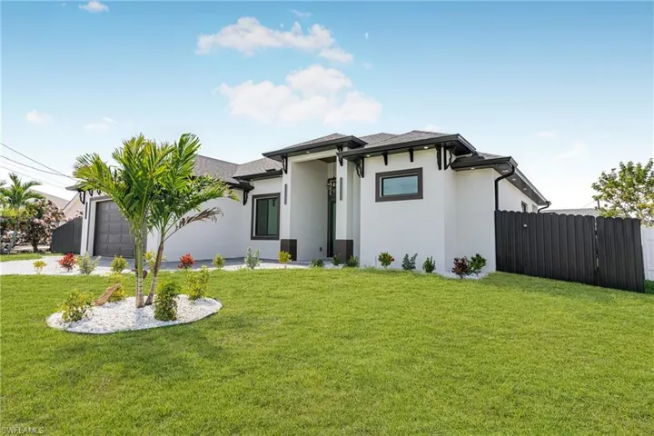 Prairie-style home with a front lawn, driveway, an attached garage, and stucco siding