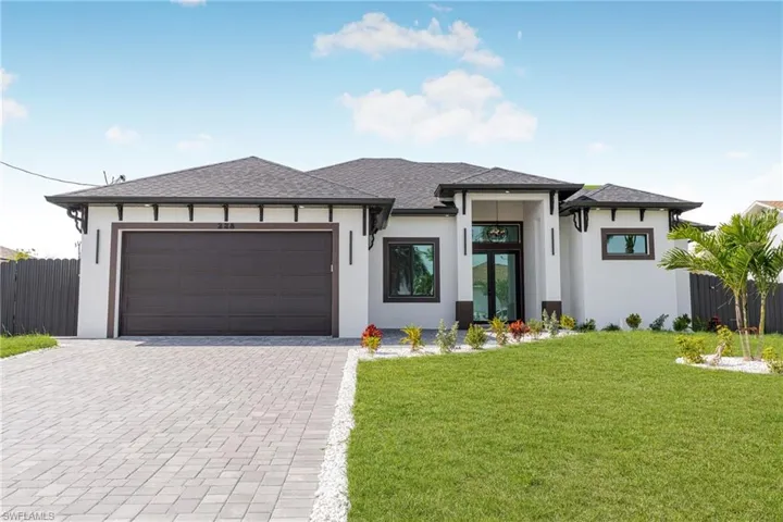 Prairie-style house featuring a garage, fence, decorative driveway, and stucco siding