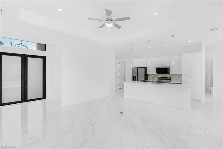 Unfurnished living room with recessed lighting, visible vents, marble finish floor, a raised ceiling, and crown molding