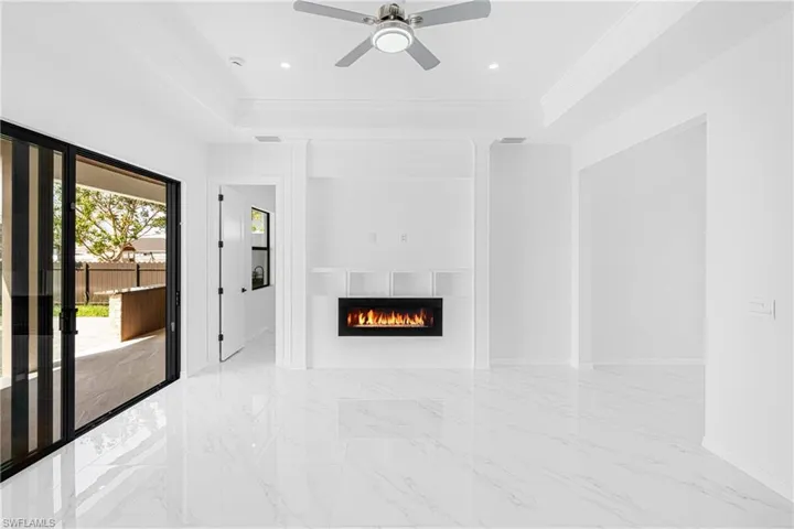 Unfurnished living room with a raised ceiling, crown molding, and marble finish floor