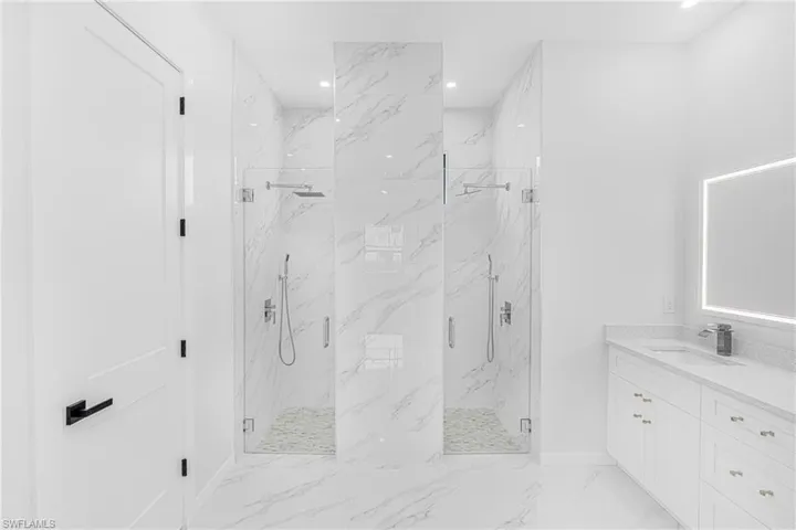 Bathroom with recessed lighting, marble finish floor, vanity, and a marble finish shower